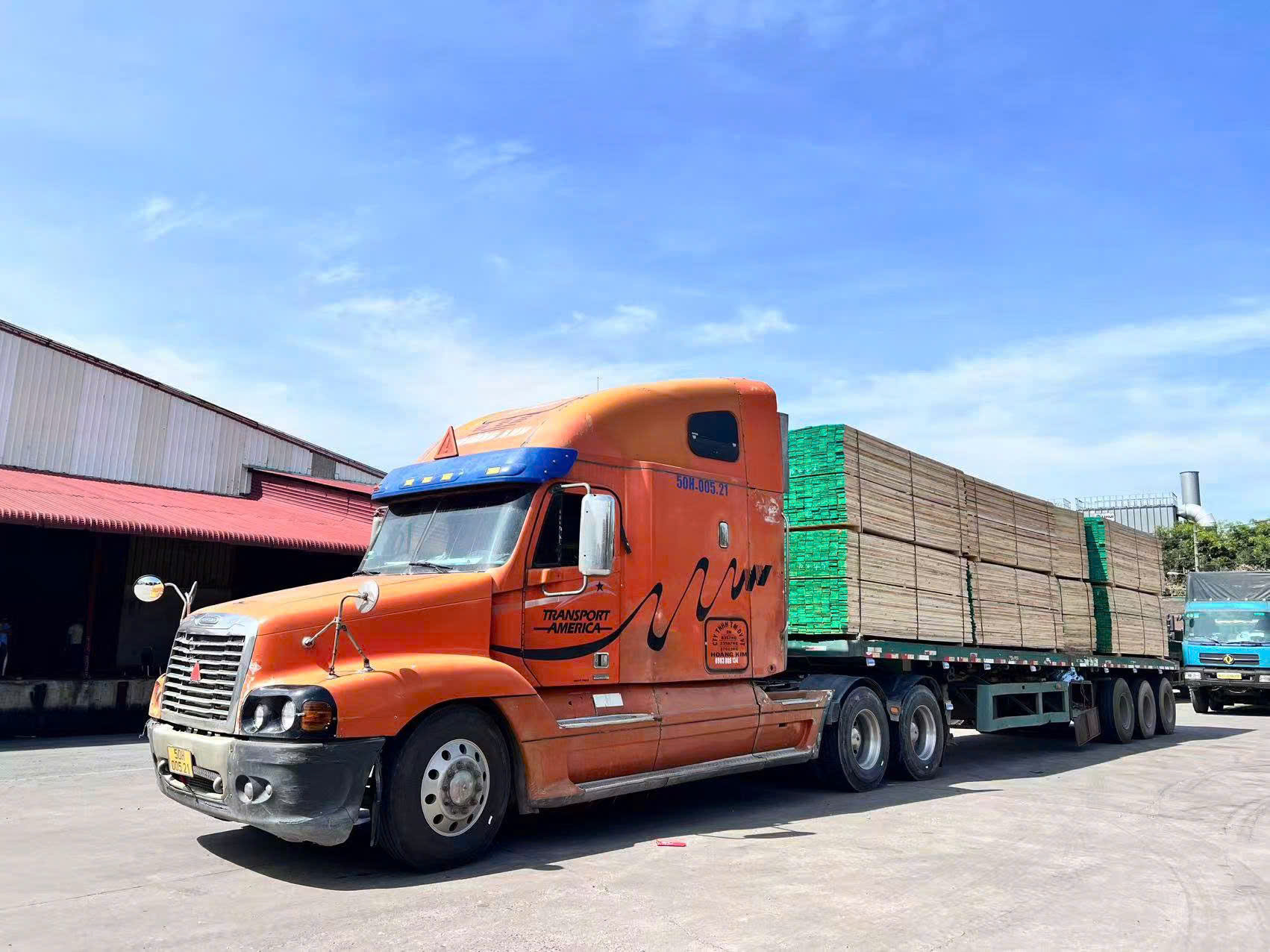 Orange semi-truck loaded with timber